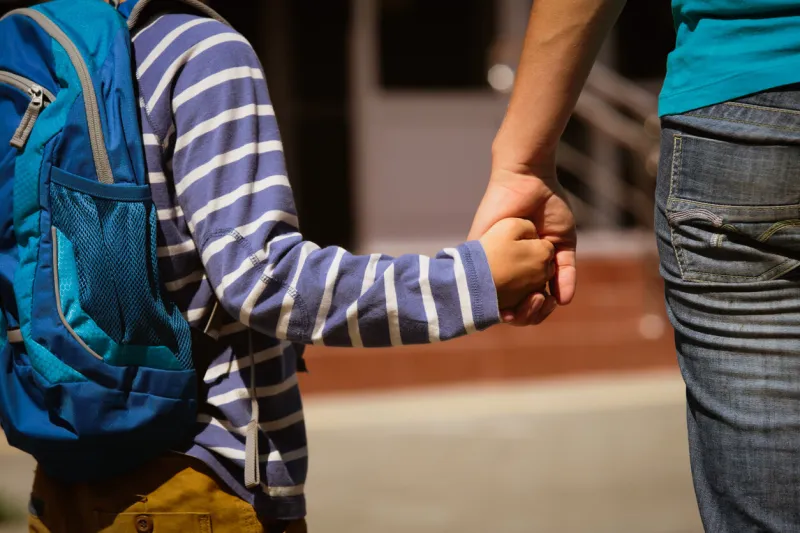 going to school- mother holding hand of son on street