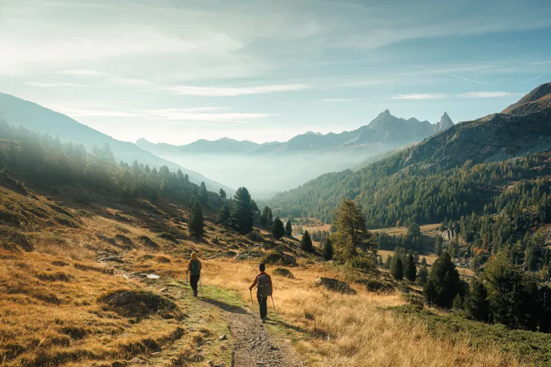 beautiful french alps scenery with couple of hiker hiking in claree valley and foggy on hill in the morning on autumn at hautes alpes, france