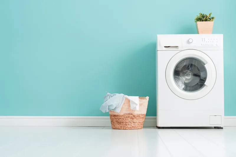interior of laundry room with a washing machine on bright teal wall background