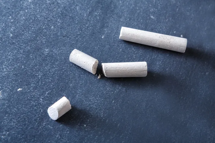 education background and school - pieces of chalk on blackboard surface, close-up, copy space, object