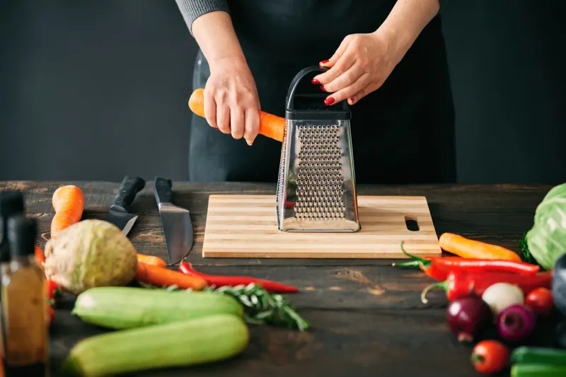 woman cooking in kitchen at home cropped image of female hands rubs carrots on a grater culinary, healthy eating concept