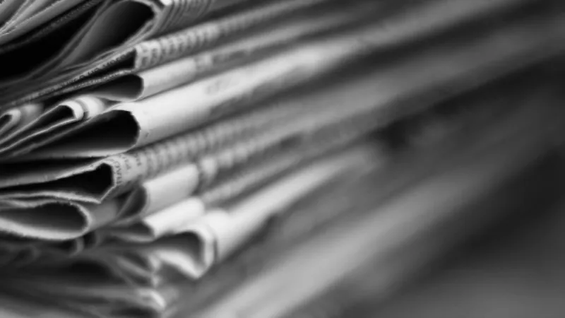 newspapers folded and stacked in a pile old journals with news on wooden table retro style, blurred background with selective focus, close up
