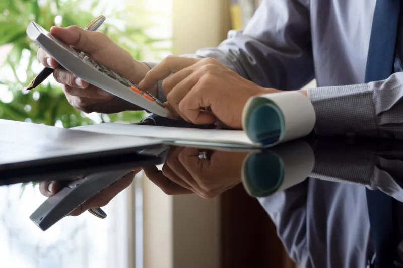 business man using calculator and sign cheque, work on laptop computer at office payment and payrol concept copy space
