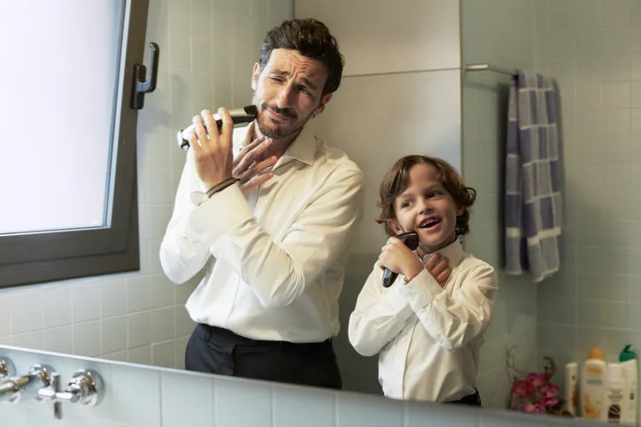 reflection of father and son shaving together in bathroom