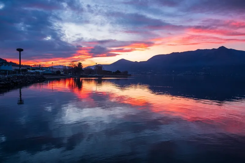 beautiful colorful sunset with clouds and mountains reflecting on lake maggiore in luino