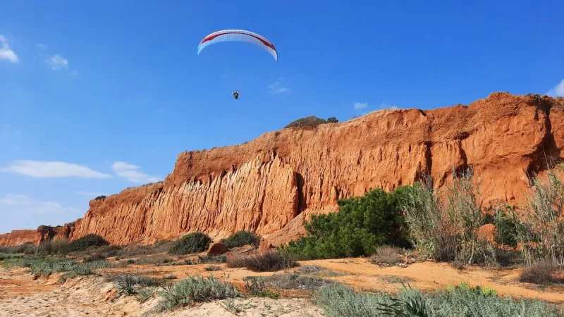 a paraglider above the beach of la falaise, in albufeira, portugal, in the algarve region