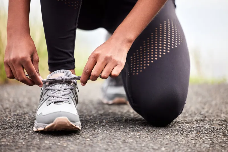 closeup shot of an unrecognizable woman tying her shoelaces while exercising outdoors