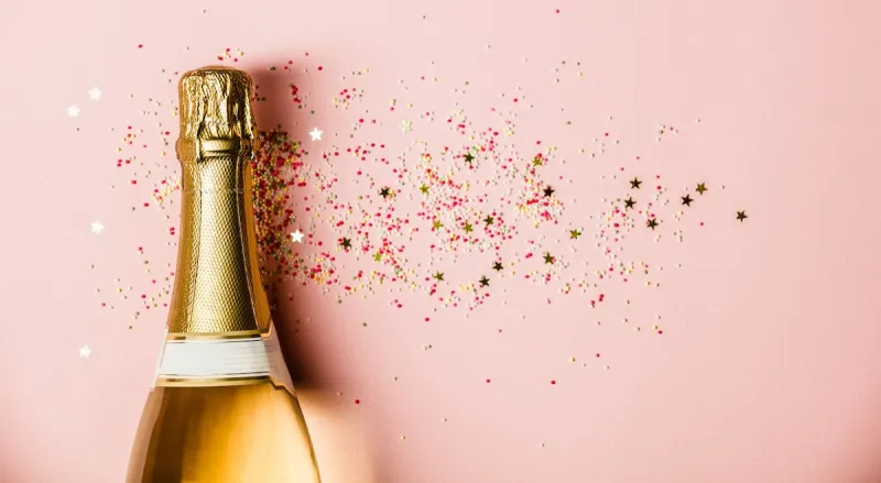 flat lay of celebration champagne bottle with ice cream sprinkles and golden star sprinkles on pink background top view (flat lay of celebration champagne bottle with ice cream sprinkles and golden star sprinkles on pink background top view, asc