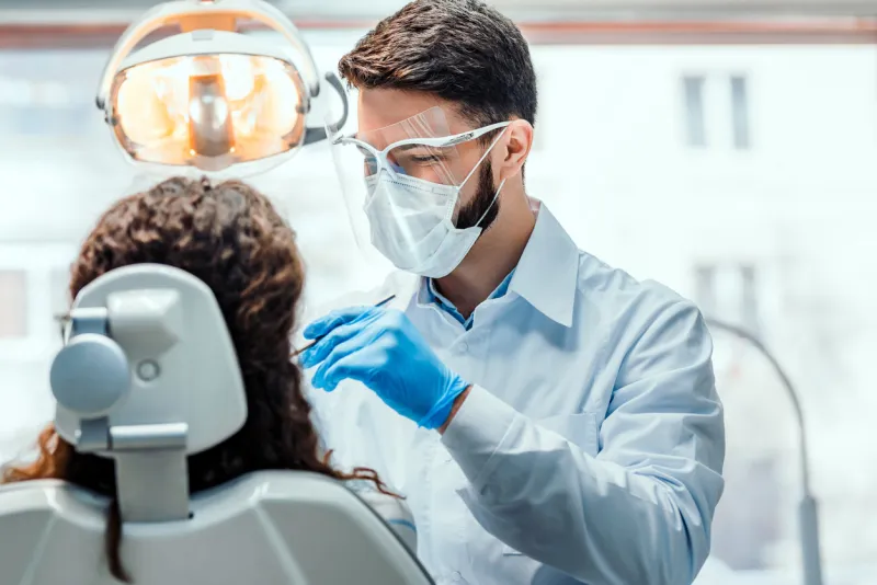 dentist working in dental clinic with patient in the chair