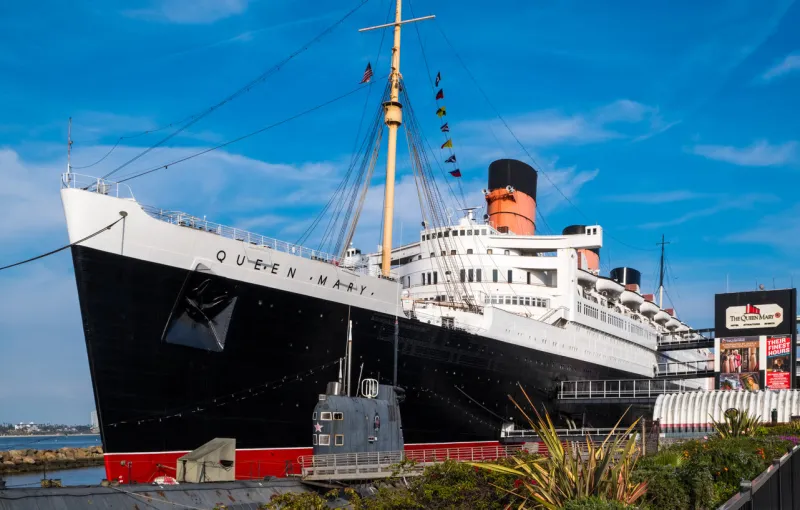 the queen mary ocean liner, now a museum and major tourist attraction docked in long beach, california, with the russian submarine 'scorpion' in front