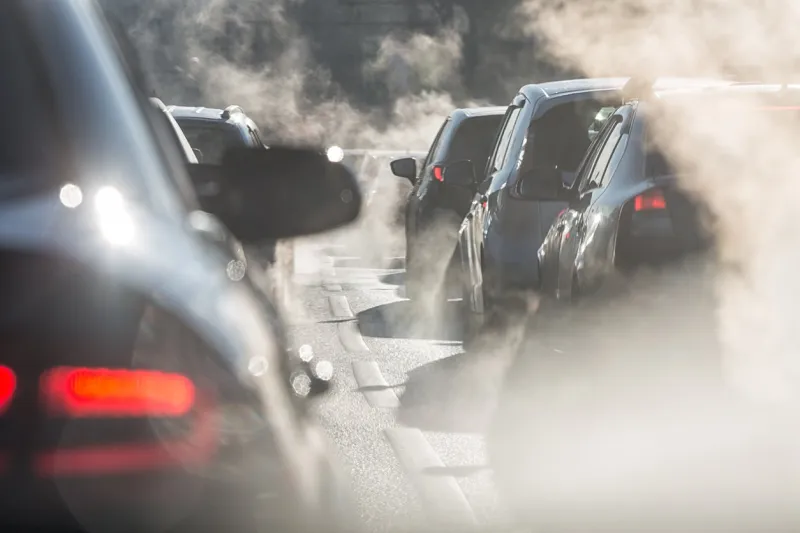 moscow, russia - august 08, 2017  traffic jam blurred silhouettes of cars surrounded by steam from the exhaust pipes environmental pollution