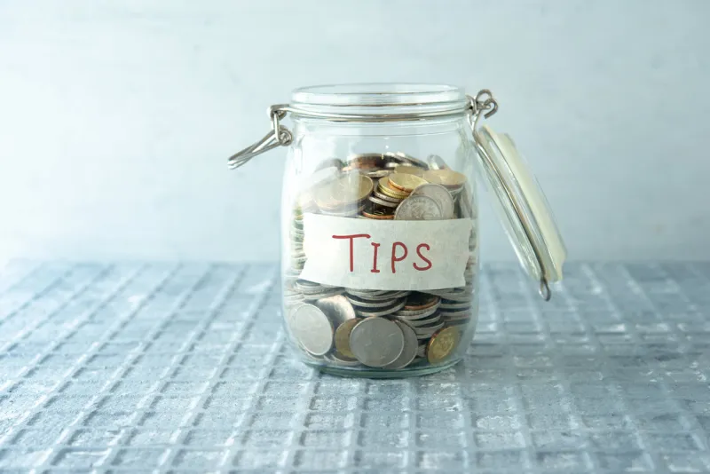 coins in glass money jar with tips label, financial concept