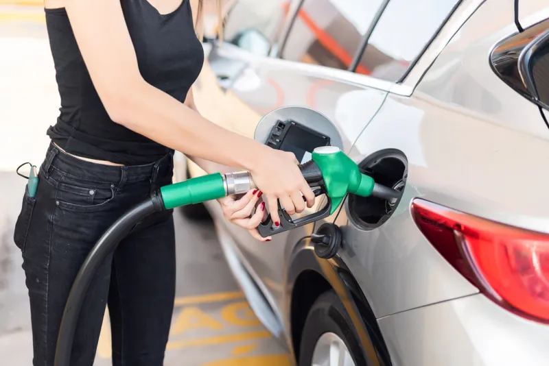 close up of a young woman getting gas in her car at a gas station