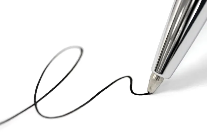macro picture of a ballpoint pen writing a signature on paper