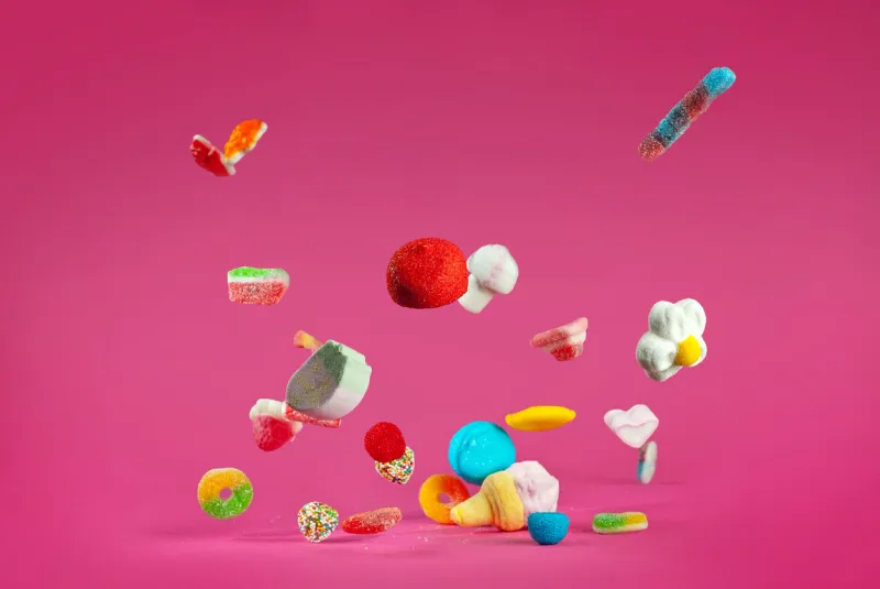 many colorful candies fall on a pink background sweets close up the concept of childhood and holidays copy space and free space for text near sweets