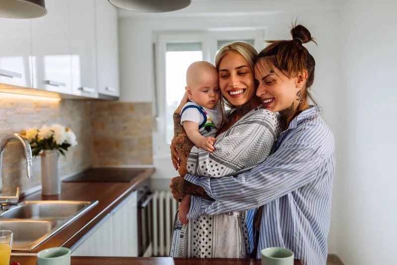 loving lesbian couple playing with their baby while spending time together at home