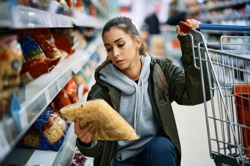 young woman buying pasta in supermarket