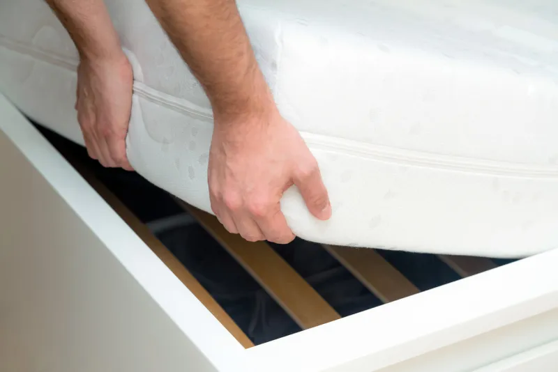 man hands lifting the mattress at the bedroom looking at the bed frame, inspects the mattress