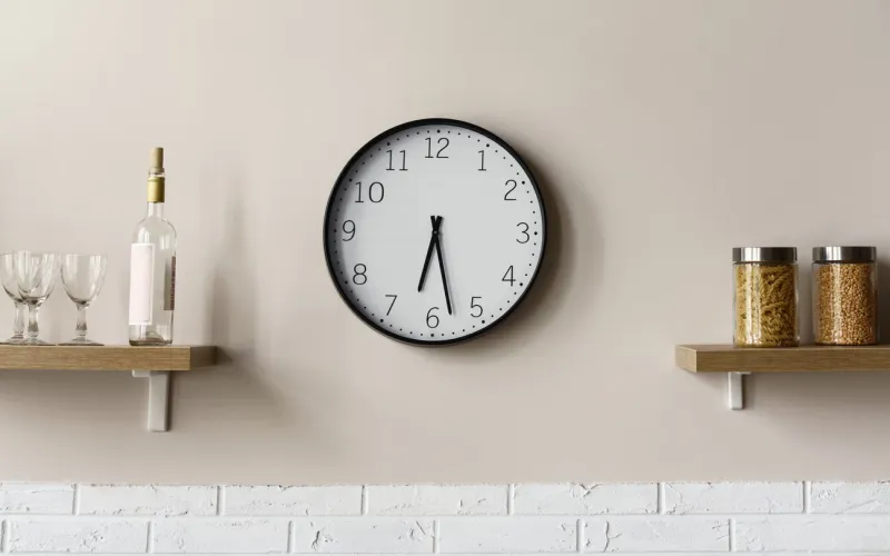 round wall clock between wooden kitchen shelves showing time