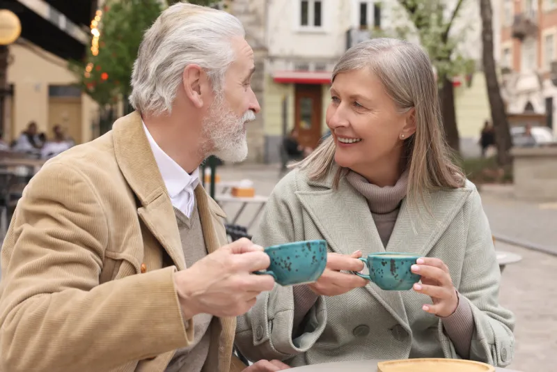portrait of affectionate senior couple drinking coffee in outdoor cafe