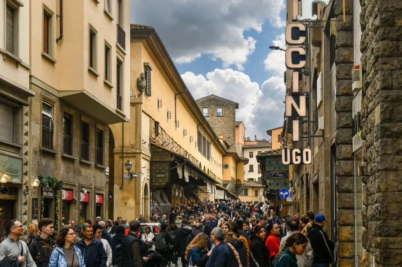 view of the ponte vecchio, a medieval closed arch bridge over the arno river, home to jewellery and art galleries, crowded with people during the easter holidays, florence, tuscany, italy