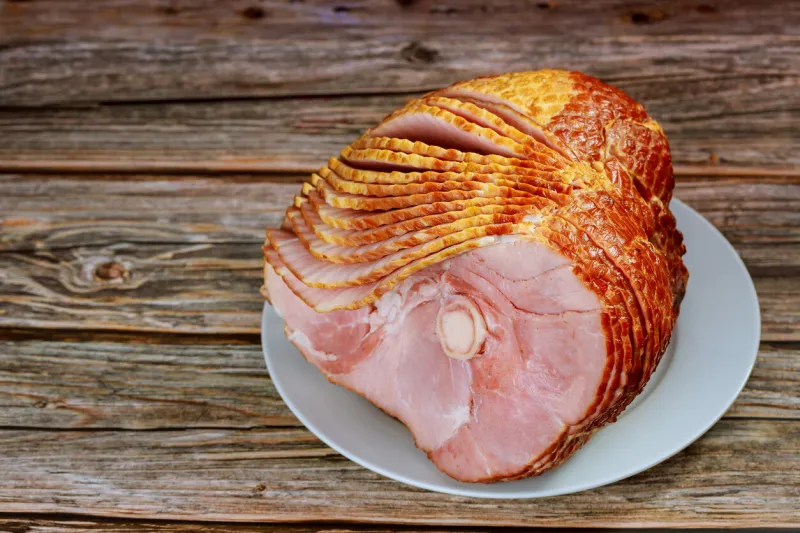 close up of sliced honey smoked ham on wooden table copy space