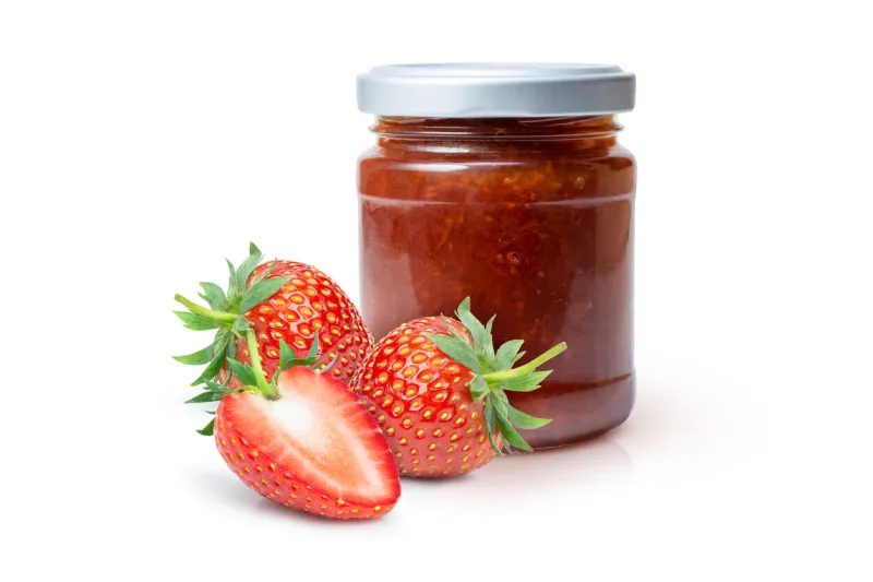 red strawberry berry jam in glass bottle and fresh strawberries fruit isolated on white background