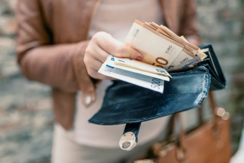 woman holding in hands wallet with euro money city girl is taking out money from wallet