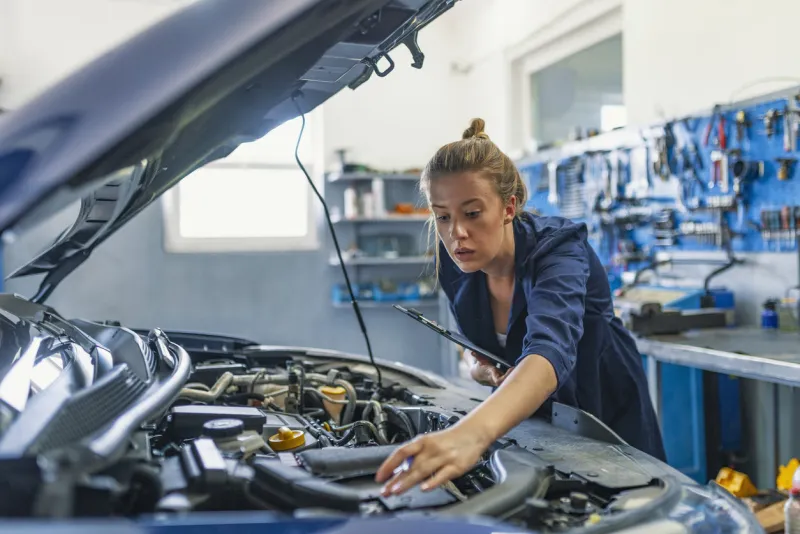 mechanic working under the hood at the repair garage portrait of a happy mechanic woman working on a car in an auto repair shop female mechanic working on car