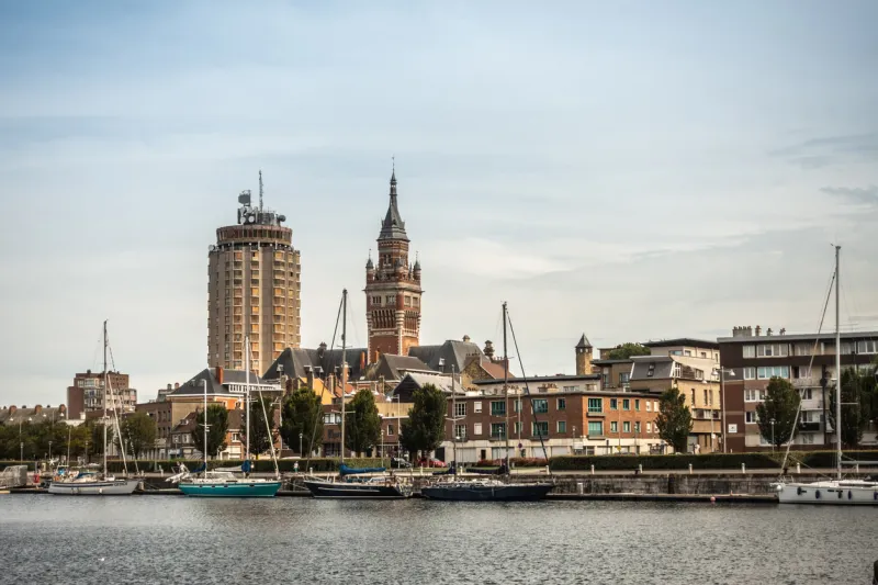 dunkerque, france - september 16, 2018  old port with sailing yachts and two towers  condominiums, belfry of dunkirk town hall under light blue sky red brick other buildings