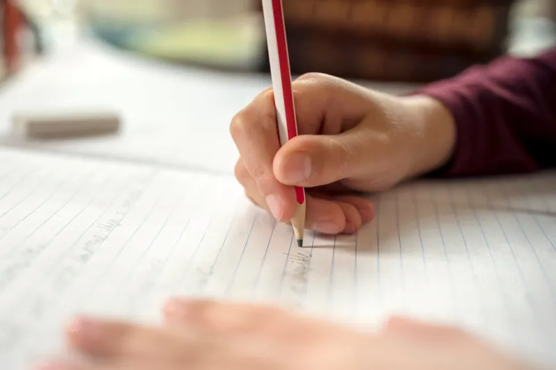 boy writing in a notepad doing his school work spelling or homework
