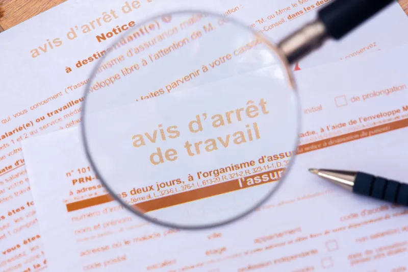 clamart, france - august 19, 2023  close-up through a magnifiying glass of an official sick leave form from the french social security that a doctor gives to patients when they are unable to work