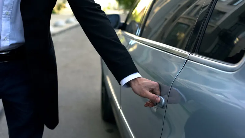 driver opening car door to young respectable oligarch, professional chauffeur