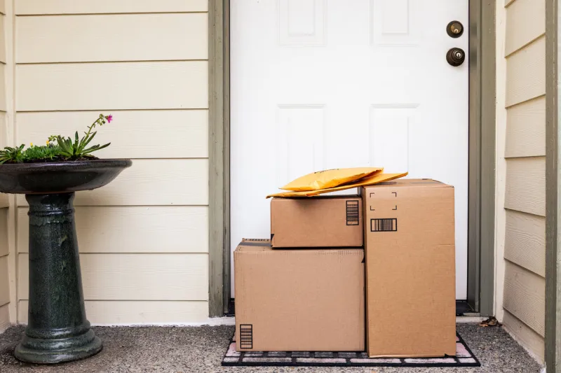 front door of house with stack of delivery boxes from online ordering and e-commerce