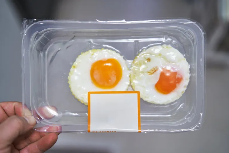point of view angle of a person holding a plastic package of grilled eggs   fried eggs ready to eat with microwave