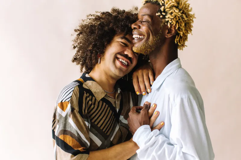 cheerful young gay couple standing together in a studio two affectionate male lovers smiling cheerfully while embracing each other against a studio background young gay coupe being romantic