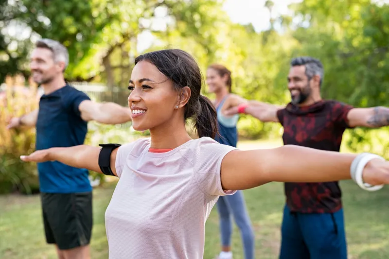 group of multiethnic mature people stretching arms outdoor middle aged yoga class doing breathing exercise at park beautifil women and fit men doing breath exercise together with outstretched arms