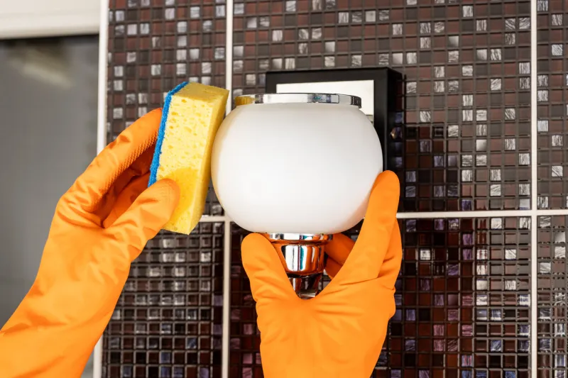cleaning service concept person dusting and washing wall light