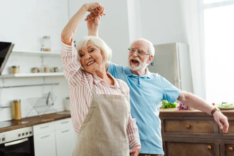 selective focus of smiling senior couple dancing in kitchen