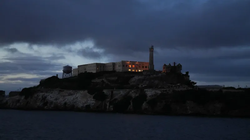 eerie night scene of alcatraz island with a spooky sky the ominous clouds and dim moonlight create a haunting atmosphere, casting shadows on the historic prison and adding a mysterious, ghostly ambiance to the infamous landmark