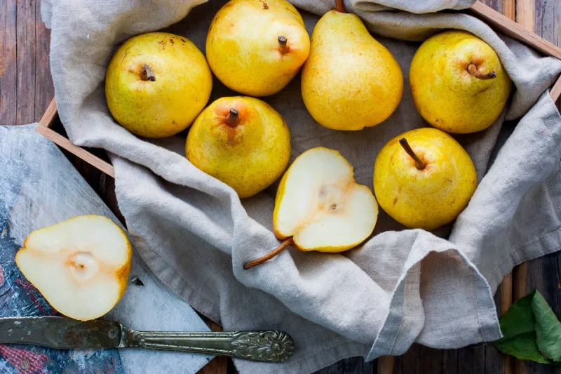 chopped fresh yellow pear on a wooden board, top view, selective focus fruit background