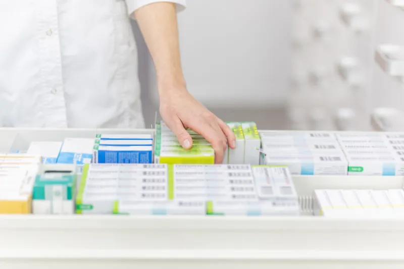pharmacist holding medicine box and capsule pack in pharmacy drugstore