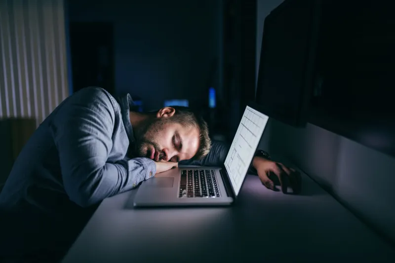 young caucasian businessman sleeping in the office late at night next to him laptop