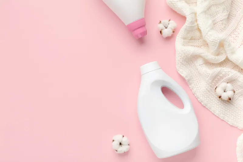 washed wool sweater with cotton flower on top bio softener will bring you real natural freshness pink background, copy space