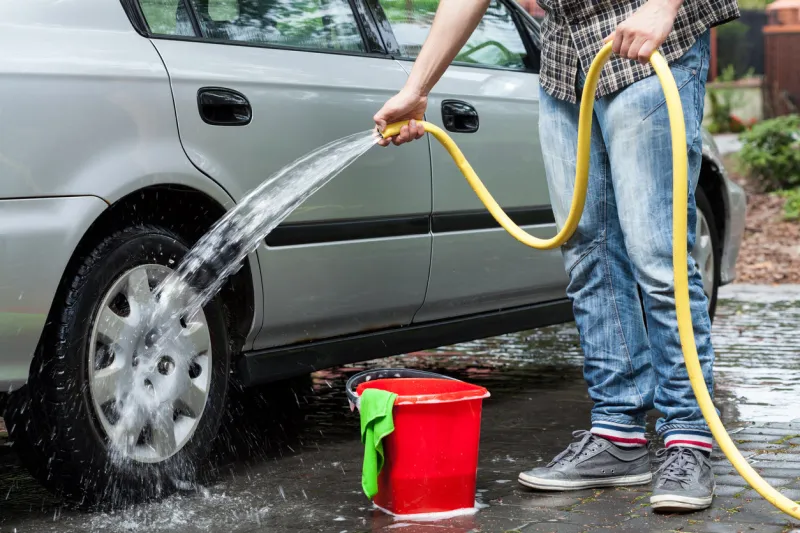 man cleaning car in front of house