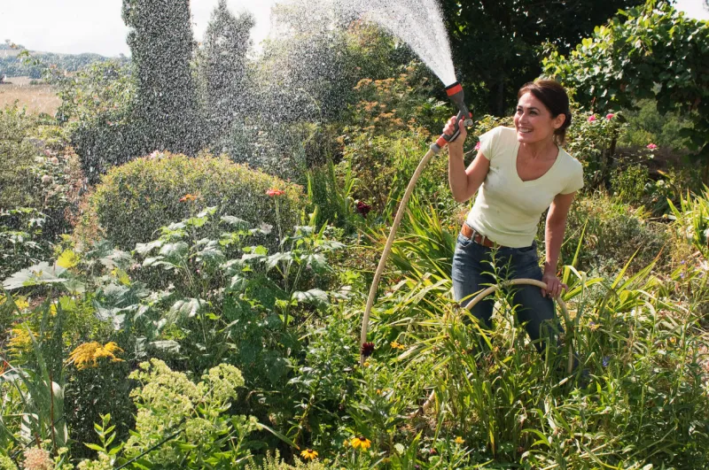 woman spraying garden with hosepipe