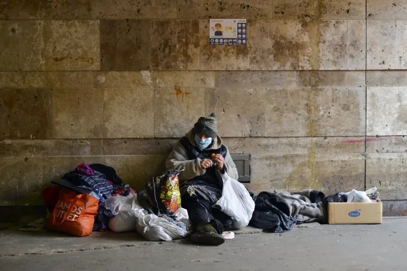 kyiv, ukraine - march 18, 2020  homeless woman in medical mask sits in an underground passage near a closed subway due to the coronavirus epidemic, the ukrainian government has closed the subway