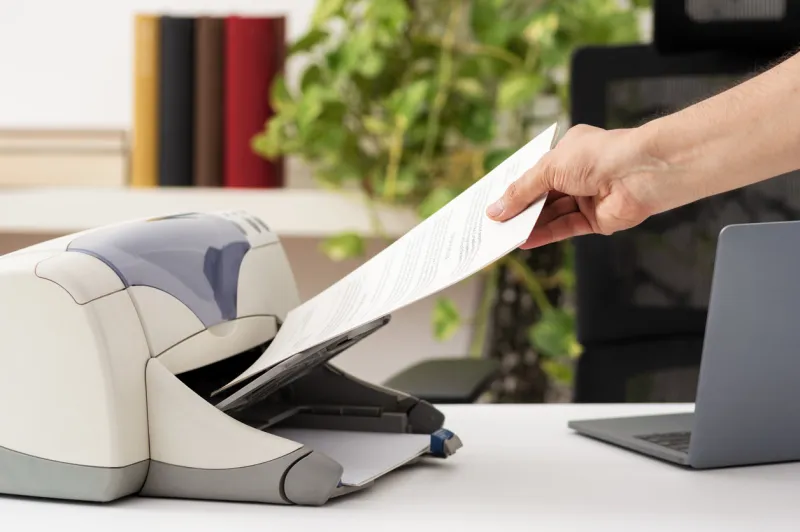 man hand catching a document from a printer at home