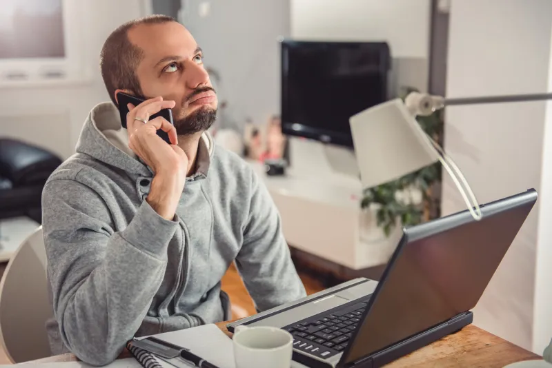 frustrated man talking on smart phone at home office