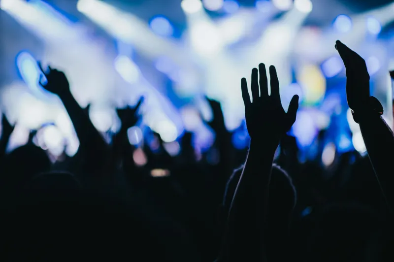 silhouette of concert crowd in front of bright stage lights on a music festival